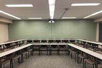 Back of room view of student tiered fixed tables and chairs seating 