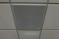 White 2x 2 tile mounted in the ceiling to provide microphone coverage over student seating