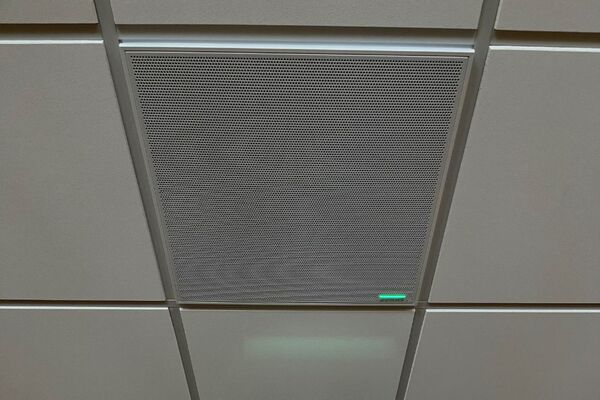 White 2x 2 tile mounted in the ceiling to provide microphone coverage over student seating