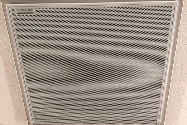 White 2x 2 tile mounted in the ceiling to provide microphone coverage over student seating