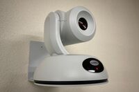 Camera mounted to a wall and instructor enabled adjustments to the lens to allow the instructor to be "seen" by the camera in more locations around the room