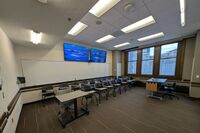 Back of room view of student tablet arm seating, confidence monitor, camera, and markerboard at rear of room