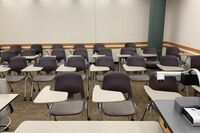 Rear of room view of student tablet arm chair seating on casters