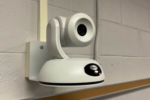 Camera mounted to a wall and instructor enabled adjustments to the lens to allow the instructor to be "seen" by the camera in more locations around the room