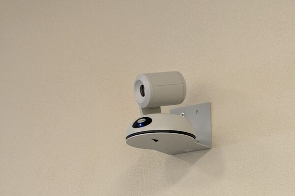 Camera mounted to a wall and instructor enabled adjustments to the lens to allow the instructor to be "seen" by the camera in more locations around the room