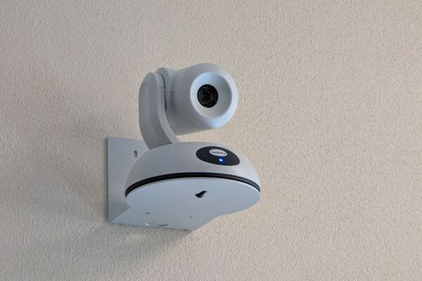Camera mounted to a wall and instructor enabled adjustments to the lens to allow the instructor to be "seen" by the camera in more locations around the room