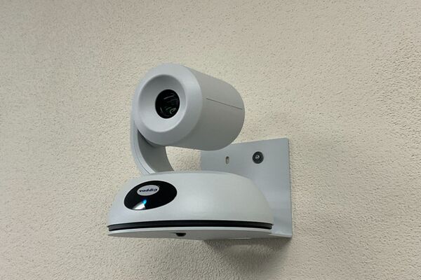Camera mounted to a wall and instructor enabled adjustments to the lens to allow the instructor to be "seen" by the camera in more locations around the room