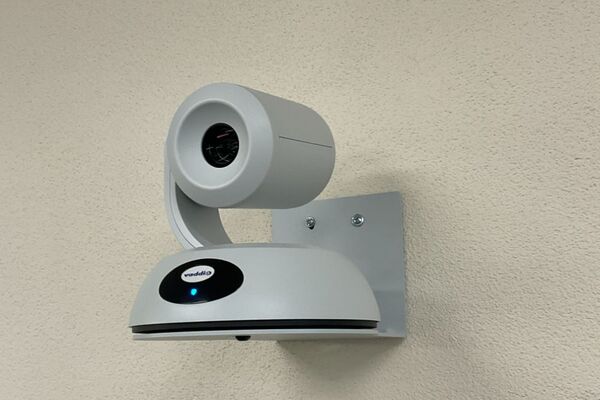 Camera mounted to a wall and instructor enabled adjustments to the lens to allow the instructor to be "seen" by the camera in more locations around the room
