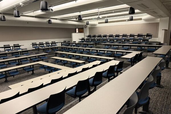 Back of room view of student fixed table and chair seating and exit doors at rear of room