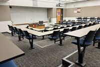 Front of room view with lectern center in front of markerboard and exit door on the right