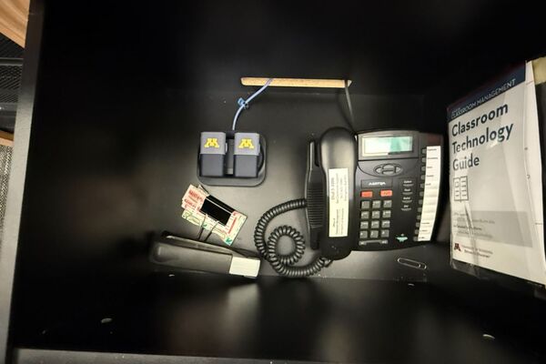 Pedestal - inside view of drawer showing two wireless mics in charging base and telephone