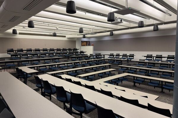 Back of room view of student fixed table and chair seating and exit doors at rear of room