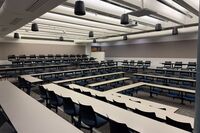 Back of room view of student fixed table and chair seating and exit doors at rear of room