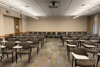 Back of room view of student tablet arm seating and exit door at left wall near rear of room