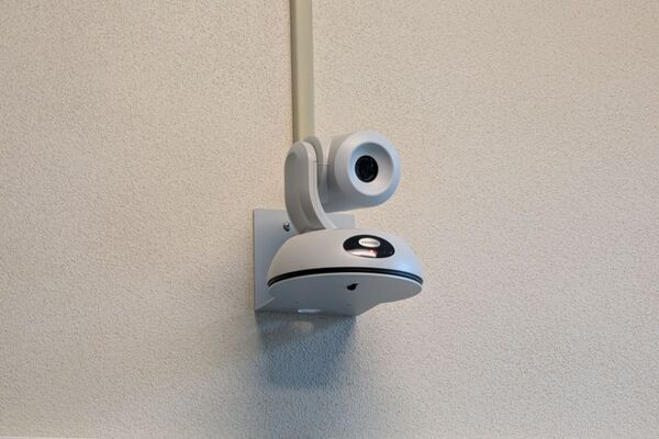 Camera mounted to a wall and instructor enabled adjustments to the lens to allow the instructor to be "seen" by the camera in more locations around the room