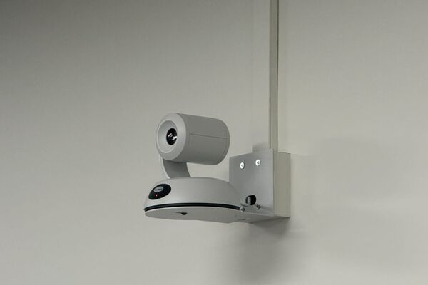 Camera mounted to a wall and instructor enabled adjustments to the lens to allow the instructor to be "seen" by the camera in more locations around the room