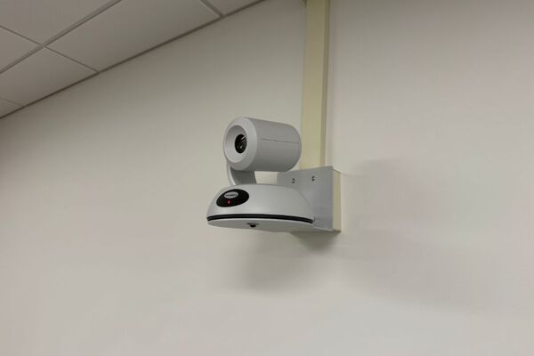Camera mounted to a wall and instructor enabled adjustments to the lens to allow the instructor to be "seen" by the camera in more locations around the room