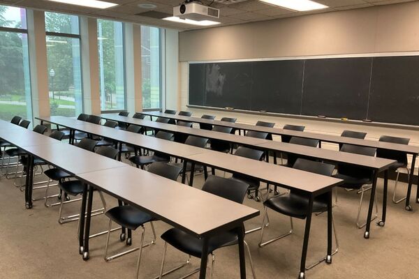 Back of room view of table and chair seating and chalkboard on rear wall