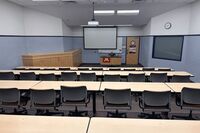 Front of room view with lectern center in front of markerboard, screen lowered