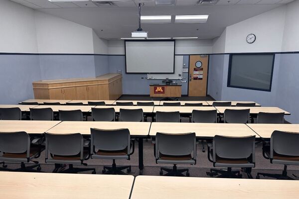 Front of room view with lectern center in front of markerboard, screen lowered