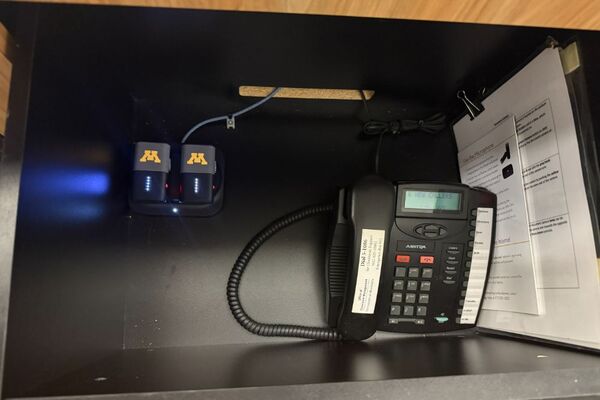 Pedestal - inside view of drawer showing two wireless mics in charging base and telephone