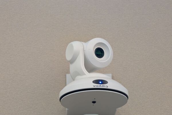 Camera mounted to a wall and instructor enabled adjustments to the lens to allow the instructor to be "seen" by the camera in more locations around the room