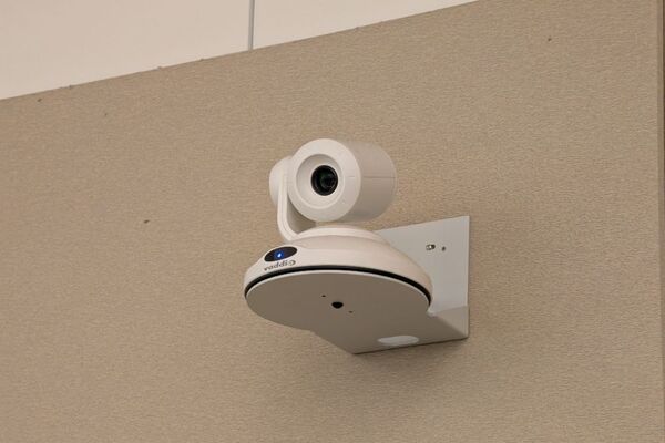 Camera mounted to a wall and instructor enabled adjustments to the lens to allow the instructor to be "seen" by the camera in more locations around the room