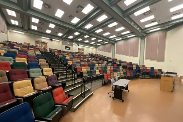 Back of room view of student auditorium seating and control room booth and double exit doors on left