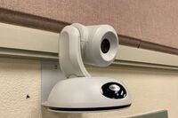 Camera mounted to a wall and instructor enabled adjustments to the lens to allow the instructor to be "seen" by the camera in more locations around the room