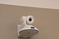 Camera mounted to a wall and instructor enabled adjustments to the lens to allow the instructor to be "seen" by the camera in more locations around the room