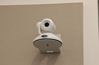 Camera mounted to a wall and instructor enabled adjustments to the lens to allow the instructor to be "seen" by the camera in more locations around the room