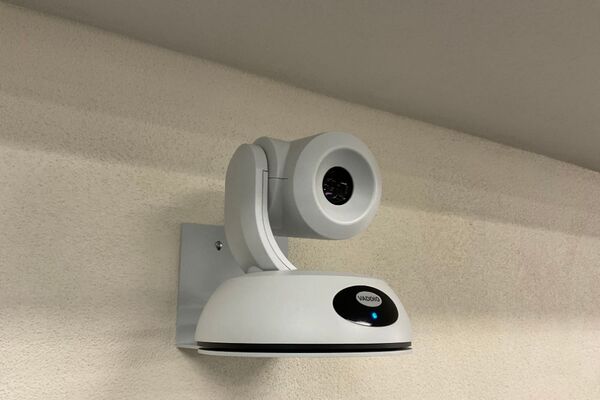 Camera mounted to a wall and instructor enabled adjustments to the lens to allow the instructor to be "seen" by the camera in more locations around the room