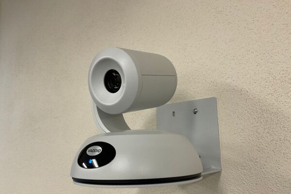 Camera mounted to a wall and instructor enabled adjustments to the lens to allow the instructor to be "seen" by the camera in more locations around the room