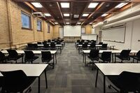 Front of room view with lectern on left,  projection screen lowered, and markerboard on the right