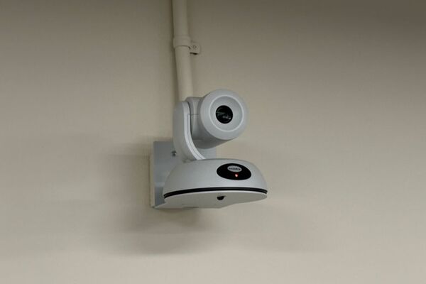 Camera mounted to a wall and instructor enabled adjustments to the lens to allow the instructor to be "seen" by the camera in more locations around the room