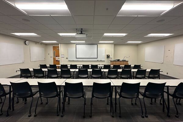 Front of room view with lectern on right in front of markerboard, door on left side