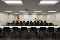 Front of room view with lectern on right in front of markerboard, door on left side