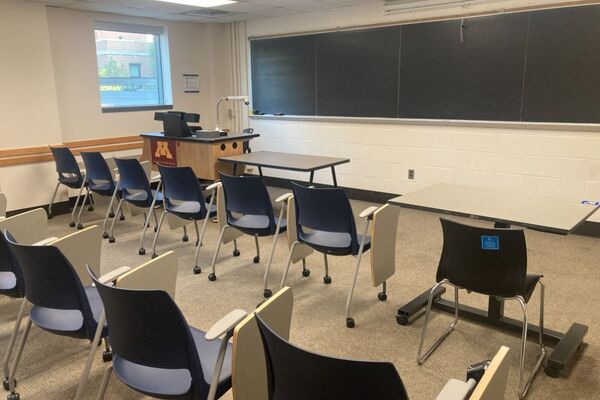 Front of room view with lectern on left in front of chalkboard and projection screen partially raised