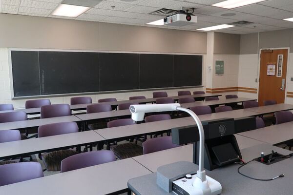 Back of room view of student tablet arm seating and chalkboard on rear wall