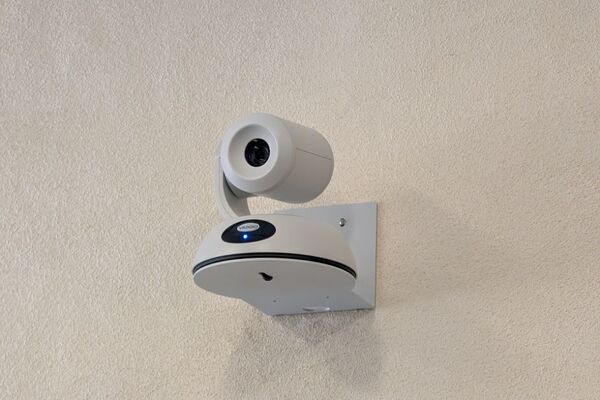 Camera mounted to a wall and instructor enabled adjustments to the lens to allow the instructor to be "seen" by the camera in more locations around the room