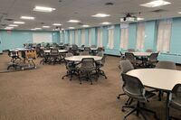 Back of room view of student round table seating and markerboard on side wall of room