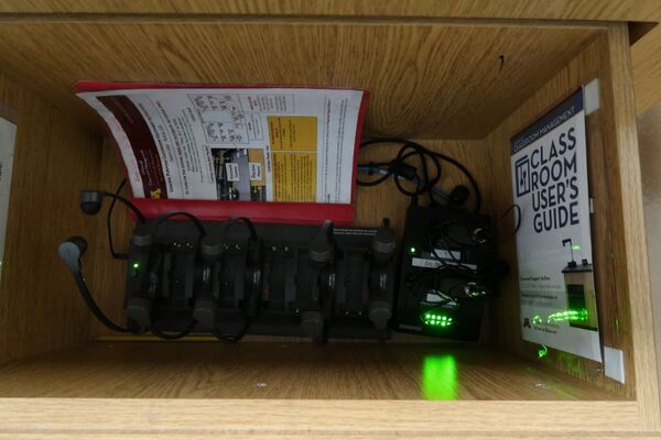 Pedestal - inside view of drawer showing wireless mics in charging base and assistive listening devices in charger