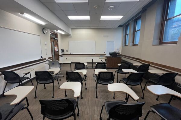 Front of room view with lectern on right in front of markerboard and  exit door on front left wall