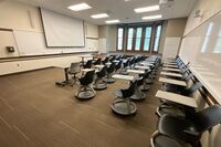 Front of room view with lectern on right in front of markerboard, screen lowered