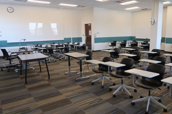 Back of room view of student tablet arm seating, multiple side markerboards, and exit door 