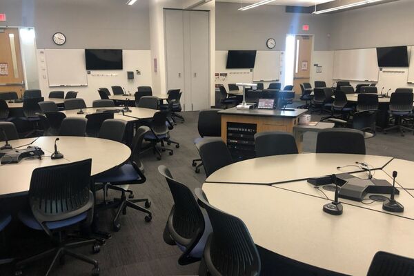 View of student collaborative table and chair seating and exit door at rear of room