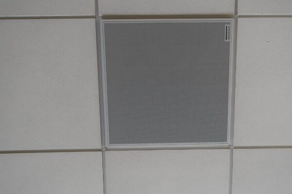 White 2x 2 tile mounted in the ceiling to provide microphone coverage over student seating