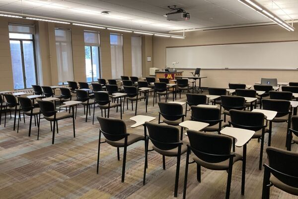 Front of room view with lectern on left in front of markerboard and exit door on right wall
