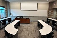 Front of room view with lectern on left in front of markerboard  with exit door to the right