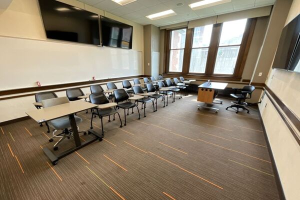 Back of room view of student tablet arm seating, confidence monitor, camera, and markerboard at rear of room